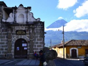 Calle de Antigua Guatemala con arquitectura colonial y volcanes al fondo.